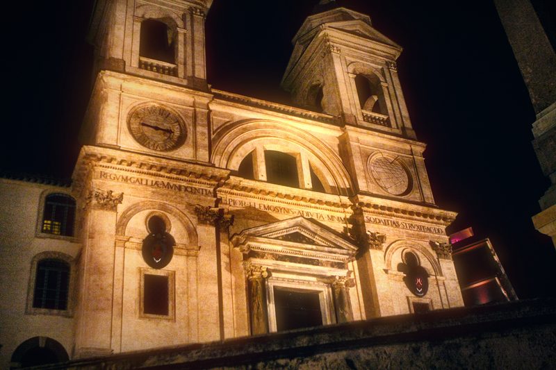 A white church facade with twin towers lit against the night.