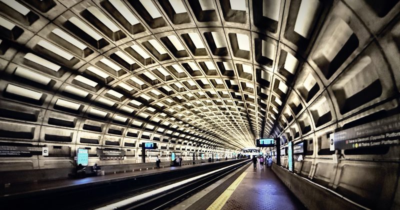 The coffered concrete vault of a subway station receding to a vanishing point.