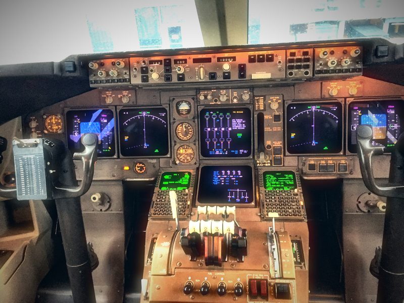 The cockpit of a 747, its screens and throttles glowing in warm amber light.