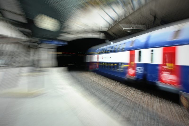Radial zoom blur of a blue and white double-deck train beside a platform.