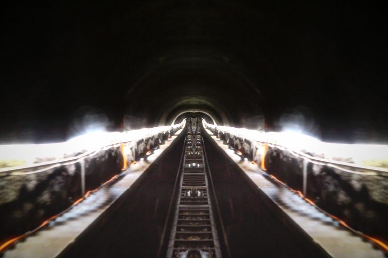 Mirrored tunnel with lit platforms on both sides and a track down the middle.