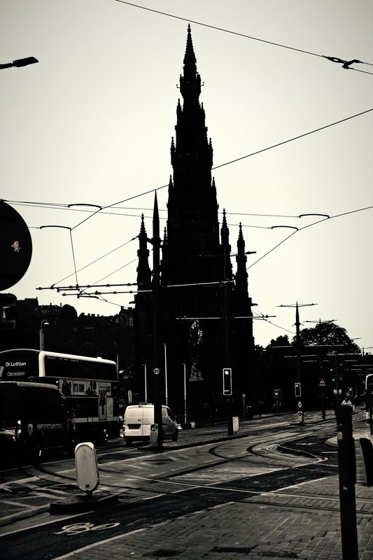 High-contrast silhouette of a Gothic spire crossed by tram wires.