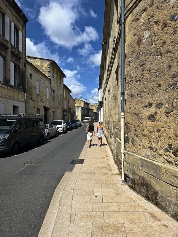 A long narrow street of stone houses with one side in shadow and one in sun.