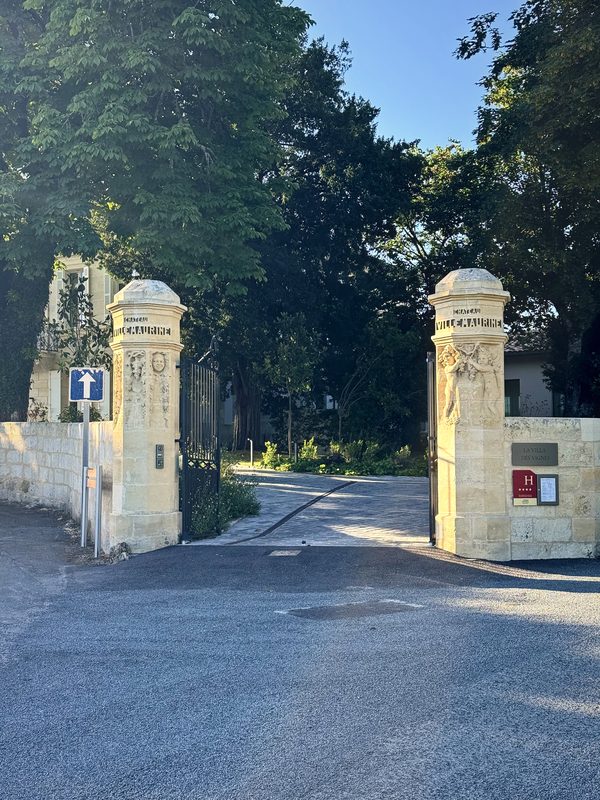 Two pale stone gateposts at the entrance to a tree-shaded lane.