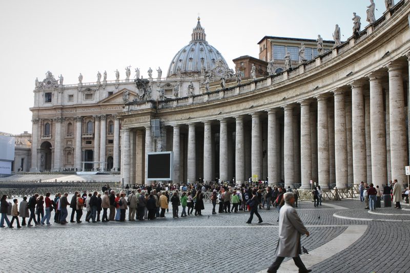 St Peter's Basilica and colonnade with a queue across the square.