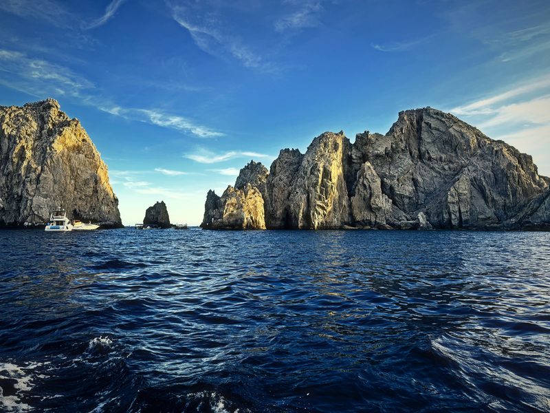 Towering granite cliffs and sea stacks above choppy blue water.