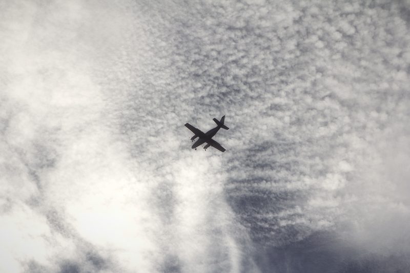 A twin-engine airplane silhouetted against a rippled, mackerel-pattern sky.