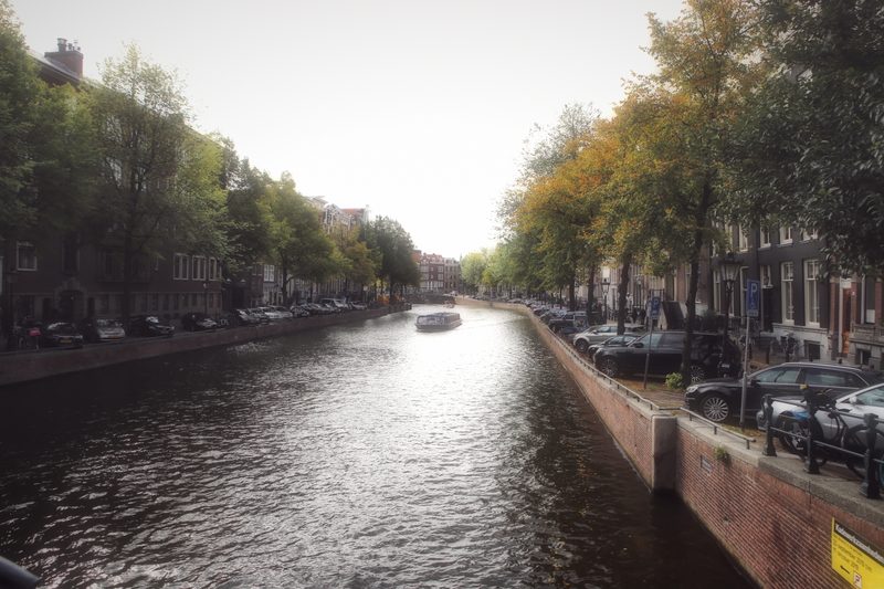 A long canal with trees on both sides under a bright, washed sky.