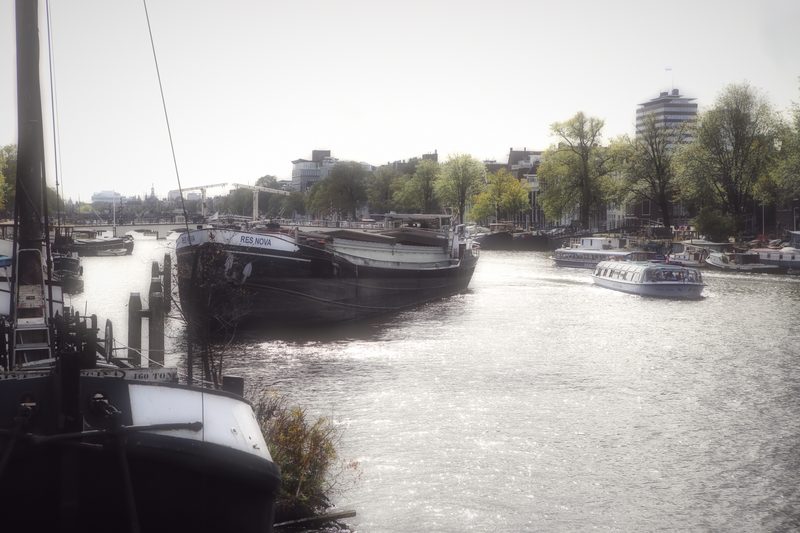 Old barges moored along a river under a pale sky.