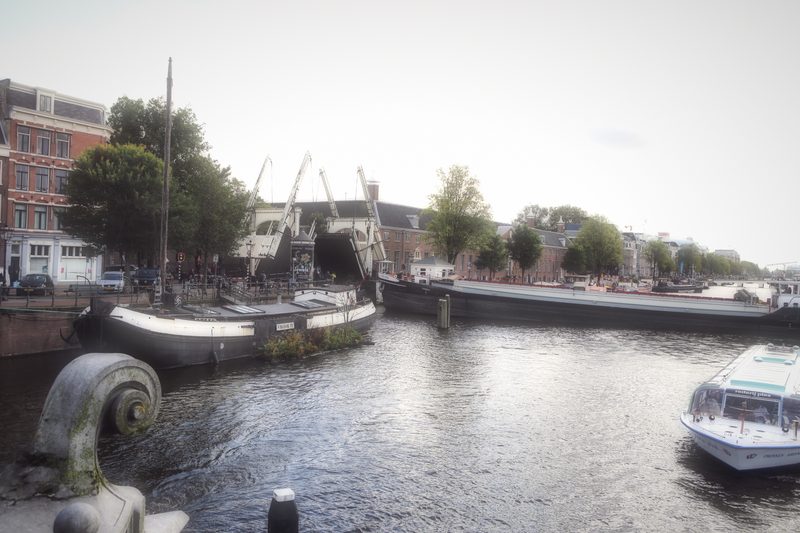 A small drawbridge and moored boats on open water, a motorboat in the foreground.