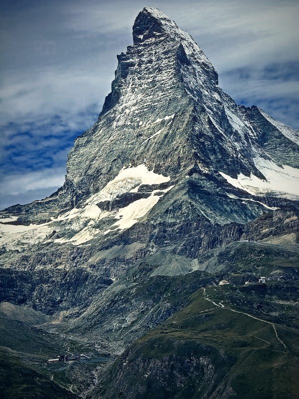 Close view of the Matterhorn's rock face streaked with snow under a pale sky.