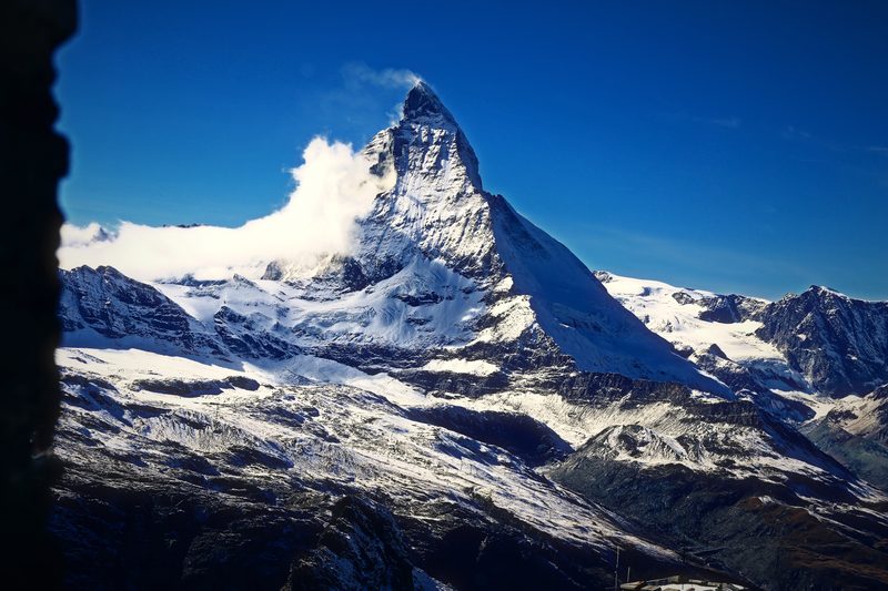 A small cloud curling off the Matterhorn's shoulder above bright snowfields.