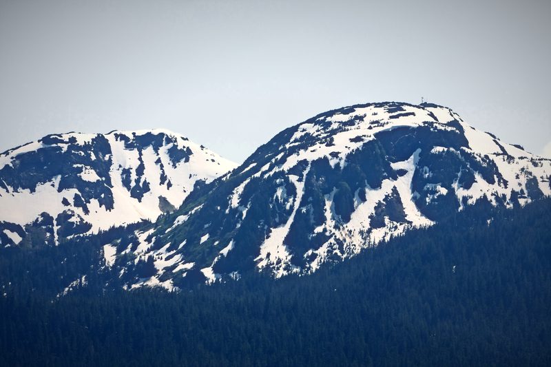 Two snowy mountain ridges side by side under a pale sky.