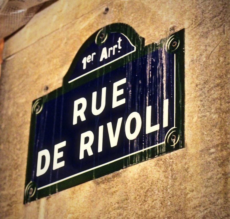 Enamel Paris street sign reading Rue de Rivoli, 1er Arrondissement, on a stone wall.