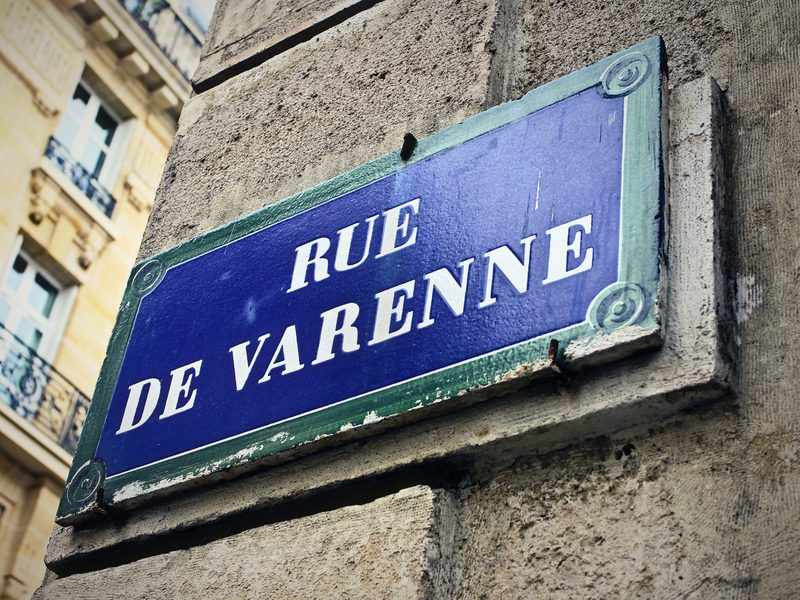 Blue enamel Paris street sign reading Rue de Varenne on a stone corner.