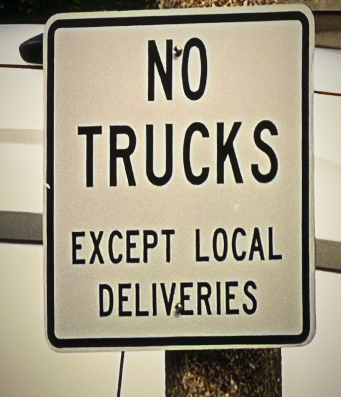 Black and white sign reading No Trucks Except Local Deliveries.