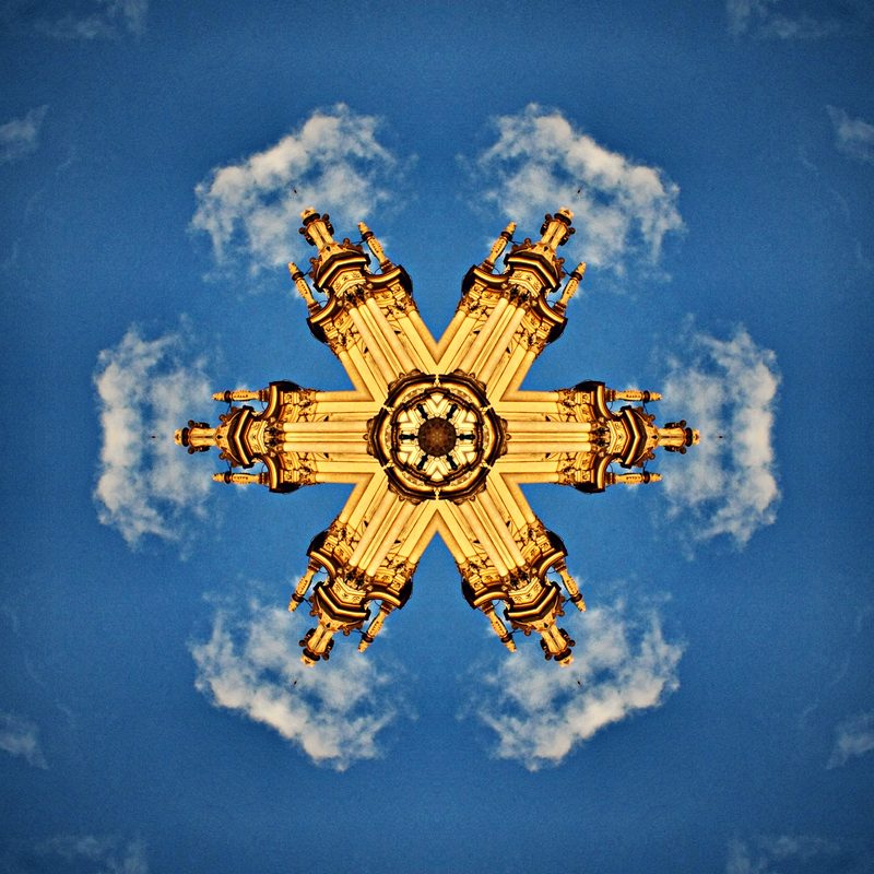 Gold arches radiating against a bright blue sky and white clouds.