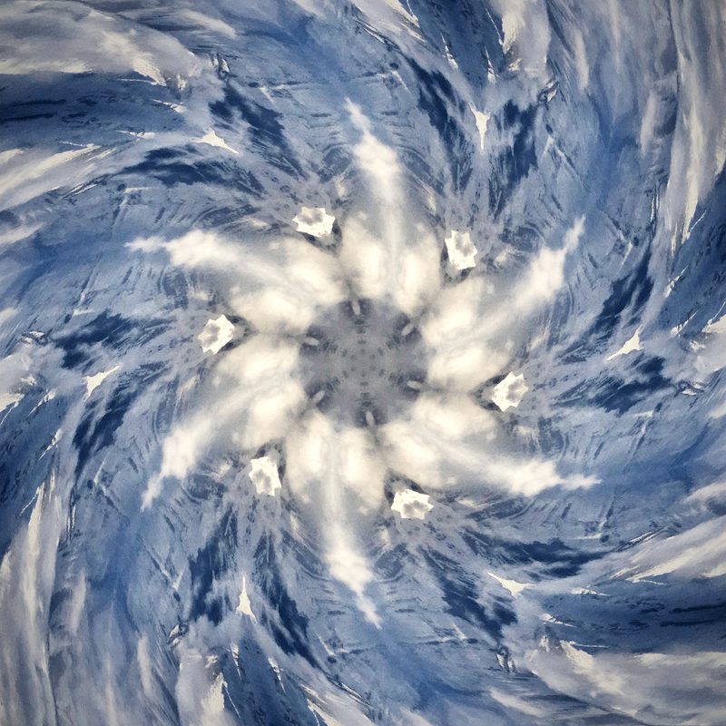 White clouds and blue sky twisting into a spiral like a turbine.