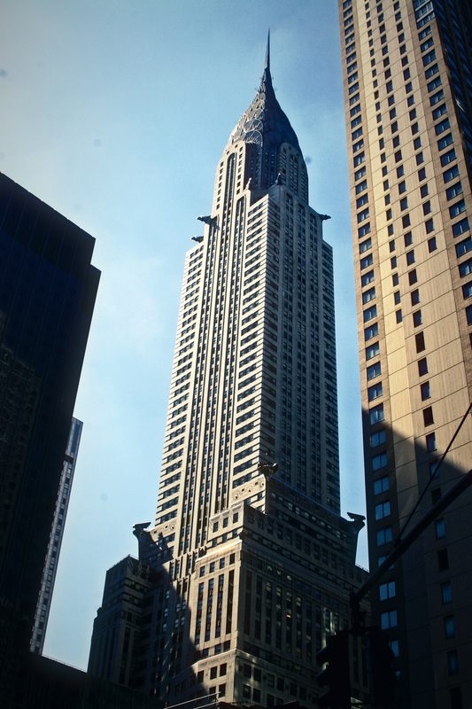 Art Deco skyscraper with a stainless steel crown rising between neighboring towers.