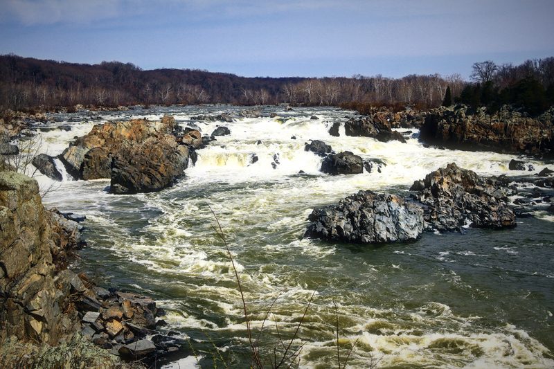 A wide rocky river breaking white across a long run of boulders.