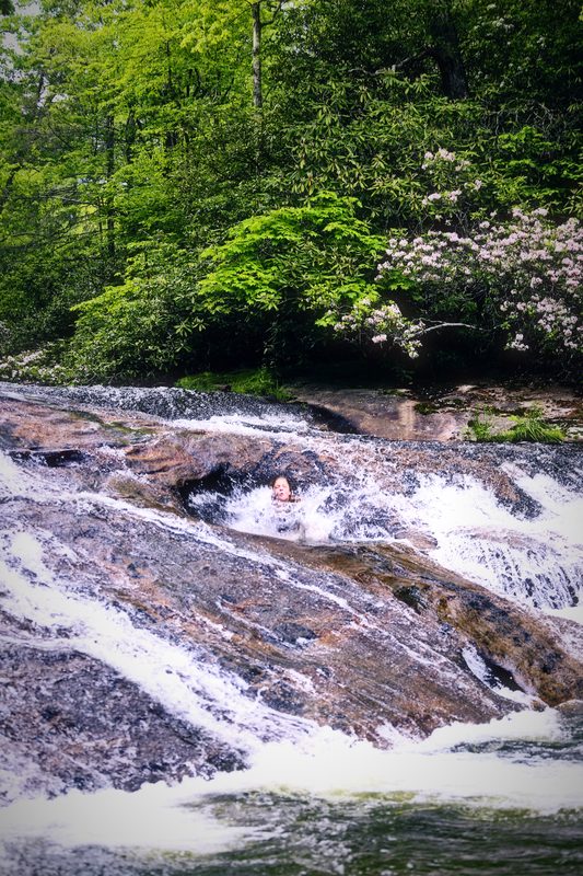 White water fanning over stepped grey rock slabs under green trees.