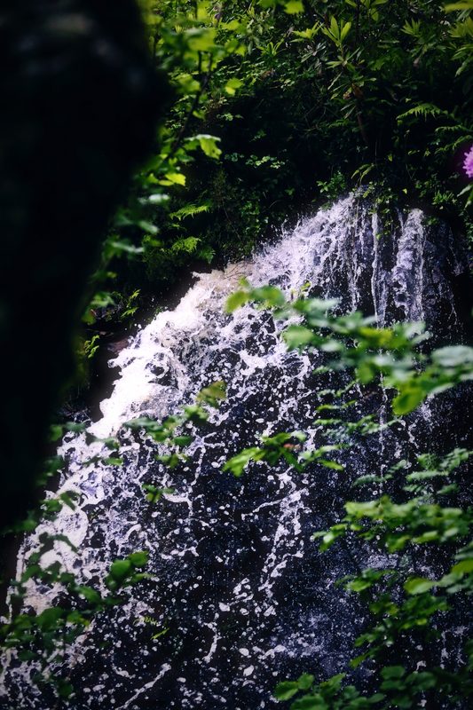 A waterfall spilling over a moss-covered rock face in deep shade.