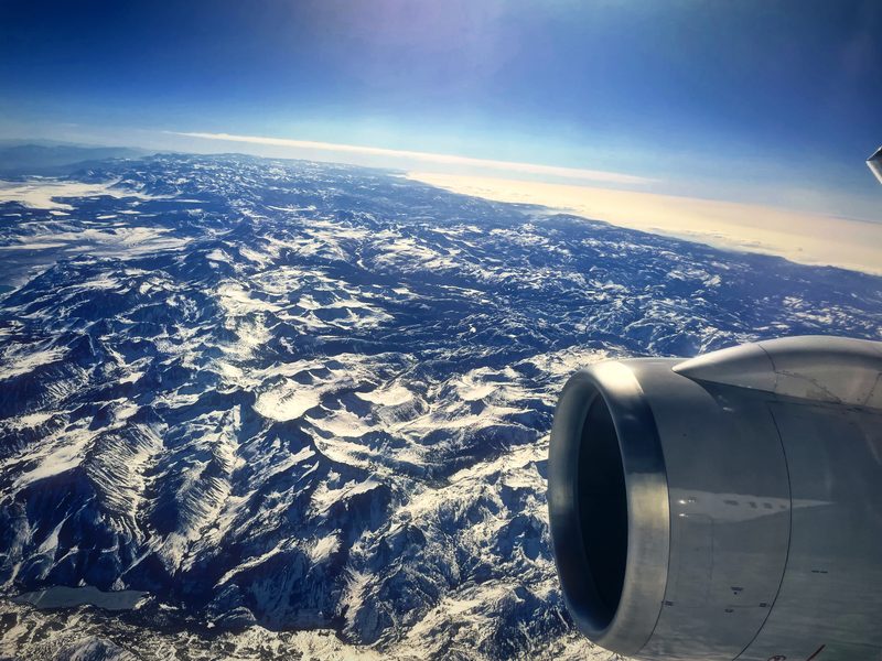 Jet engine over a range of snow-veined mountains stretching to the horizon.