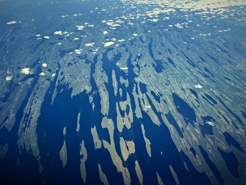 Aerial view of light and shadow breaking the land below into blue and cream shapes.