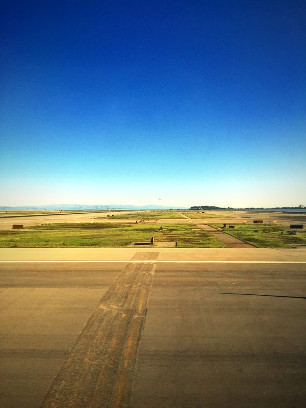 Airport taxiway and grass under a cloudless deep blue sky.