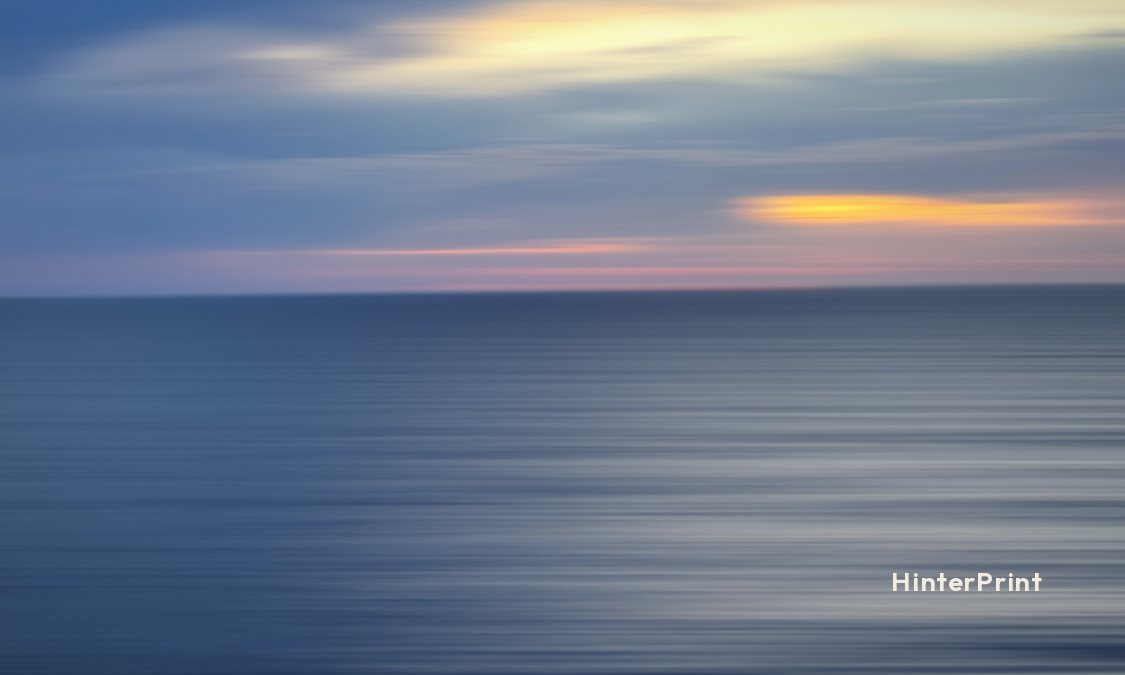 Front of the tag: a blurred blue sea under streaks of pale gold and pink cloud, with a small HinterPrint mark.